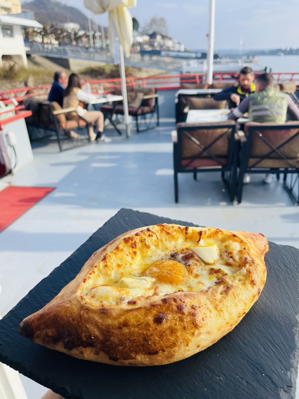 Adjarisches Khachapuri in Bootform mit geschmolzenem Käse und Ei, serviert an Deck