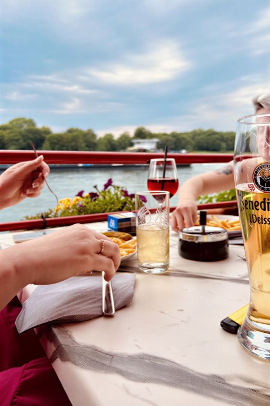 Gäste beim Anstoßen mit Weizenbier und Wein am Rheinufer